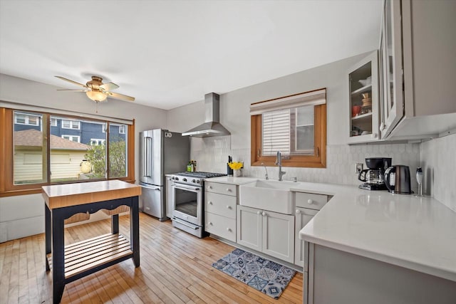 kitchen featuring a sink, appliances with stainless steel finishes, a wealth of natural light, and wall chimney range hood