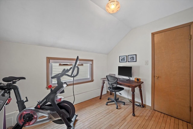 workout room with vaulted ceiling and light wood finished floors