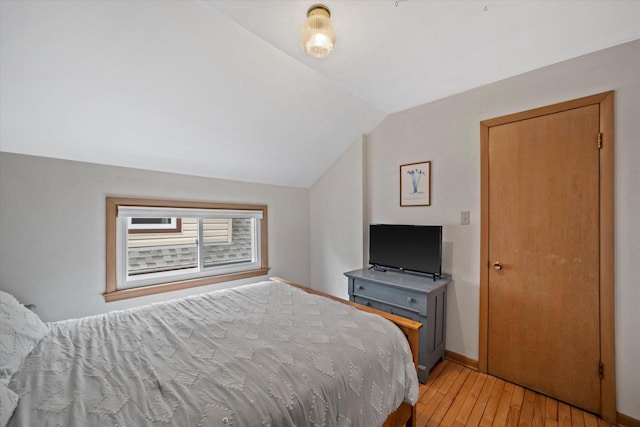 bedroom with light wood-type flooring, baseboards, and lofted ceiling
