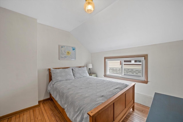 bedroom with light wood-type flooring, baseboards, and lofted ceiling