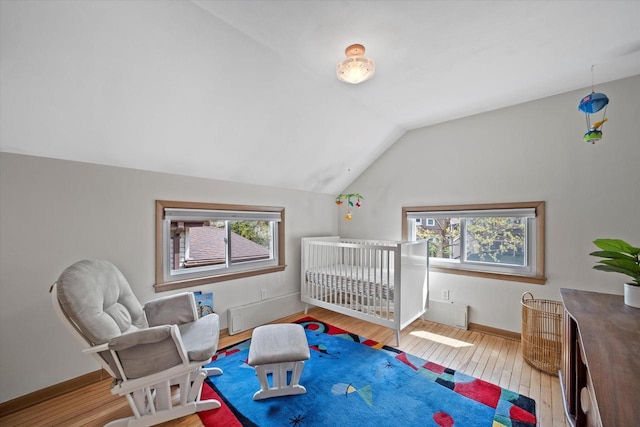 bedroom with wood-type flooring, baseboards, vaulted ceiling, and multiple windows