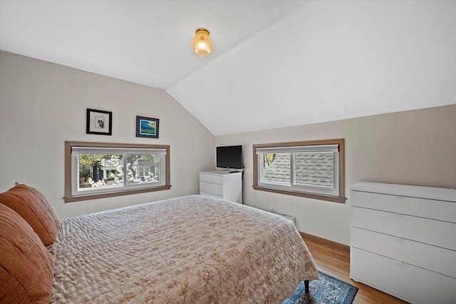 bedroom featuring baseboards, wood finished floors, and lofted ceiling