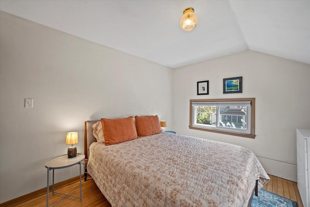 bedroom featuring baseboards, lofted ceiling, and hardwood / wood-style floors
