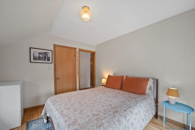 bedroom featuring baseboards, vaulted ceiling, and light wood finished floors
