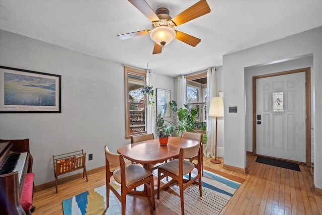 dining area featuring baseboards, a ceiling fan, and light wood-style flooring