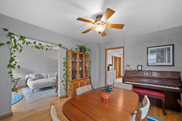 dining space featuring light wood-type flooring, a ceiling fan, and baseboards