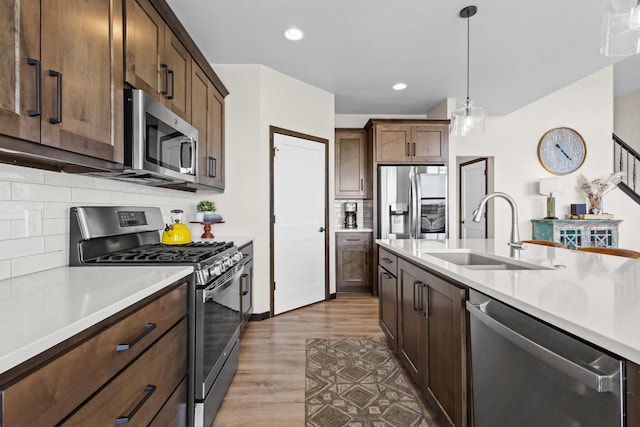 kitchen featuring light countertops, a sink, wood finished floors, and stainless steel appliances
