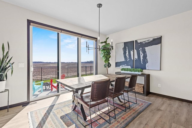 dining space with baseboards, wood finished floors, and visible vents