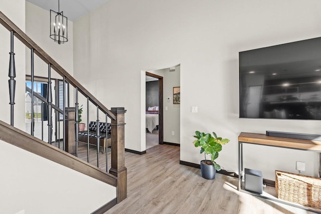 interior space with wood finished floors, baseboards, a high ceiling, stairway, and a notable chandelier