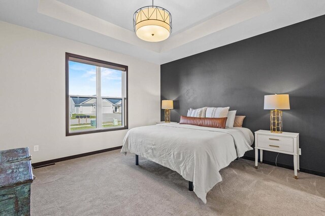 carpeted bedroom featuring baseboards and a tray ceiling