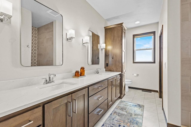 bathroom featuring double vanity, toilet, baseboards, and a sink