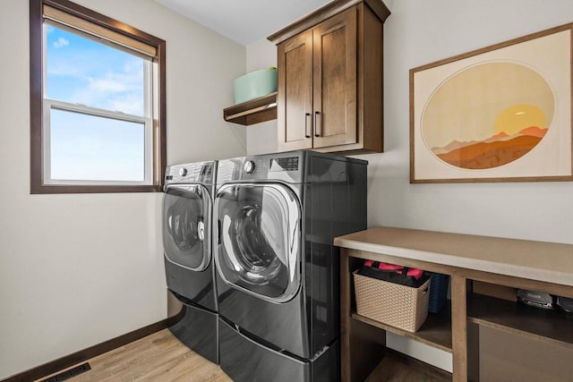 laundry area with visible vents, washer and dryer, baseboards, cabinet space, and light wood finished floors