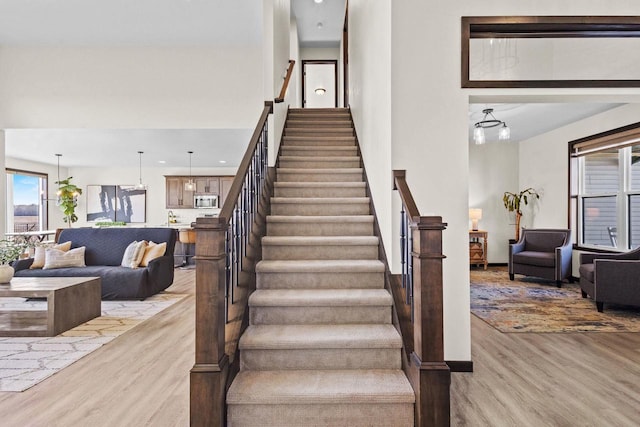 stairway with a high ceiling and wood finished floors