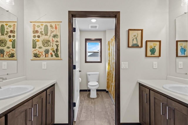 bathroom featuring a sink, baseboards, toilet, and two vanities