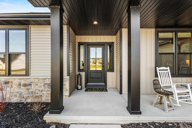 property entrance featuring a porch and stone siding
