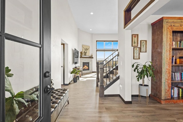 entrance foyer with baseboards, a glass covered fireplace, wood finished floors, and stairway