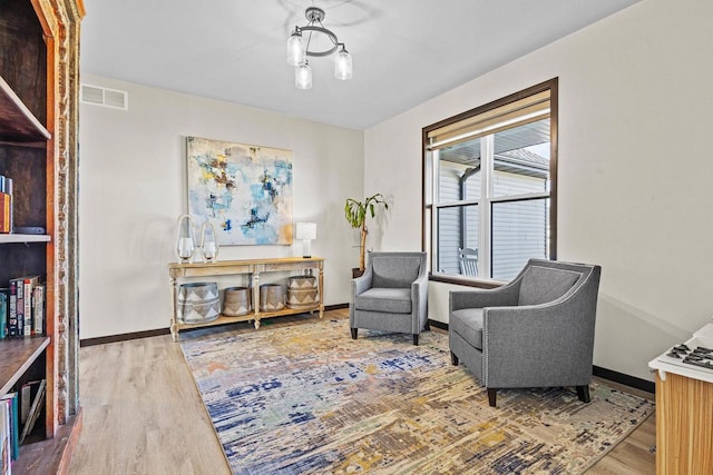 living area with baseboards, visible vents, and wood finished floors