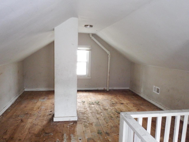 additional living space featuring baseboards, visible vents, hardwood / wood-style floors, and lofted ceiling