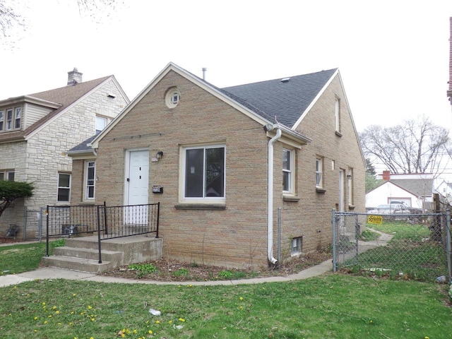 bungalow-style house featuring brick siding, fence, and a front lawn
