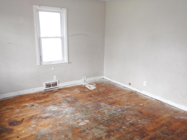 empty room featuring baseboards, hardwood / wood-style floors, and visible vents