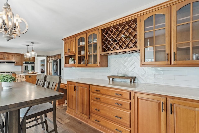 kitchen featuring wood finished floors, light countertops, under cabinet range hood, and stainless steel appliances