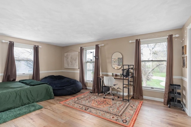 bedroom with baseboards, multiple windows, and wood-type flooring