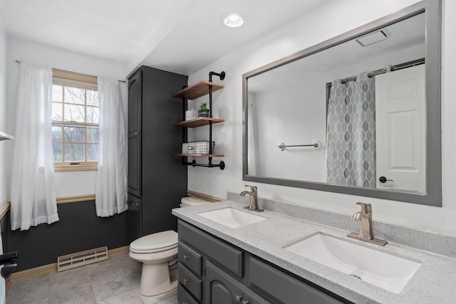 bathroom with visible vents, a sink, double vanity, and toilet