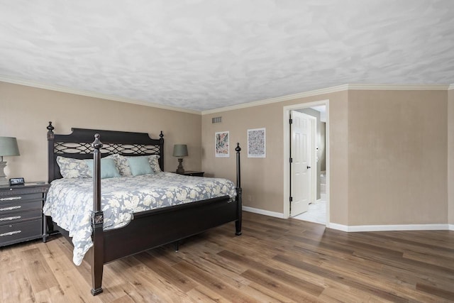 bedroom featuring baseboards, ornamental molding, wood finished floors, and visible vents