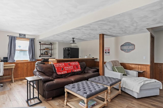 living room with a textured ceiling, wainscoting, wood finished floors, and wooden walls