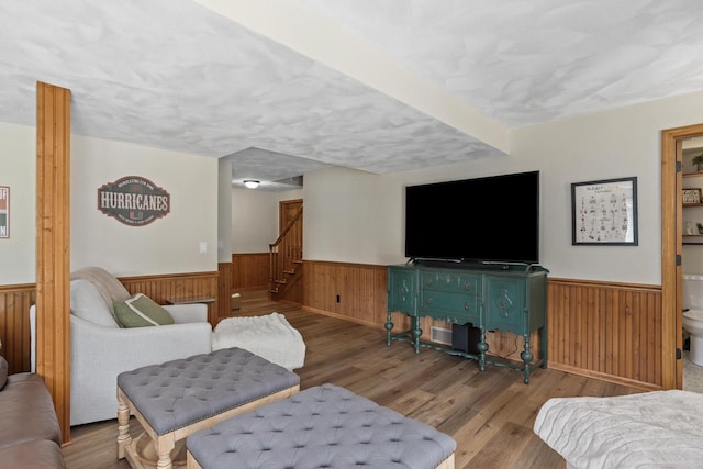 living area featuring wood finished floors, stairs, a wainscoted wall, and wooden walls