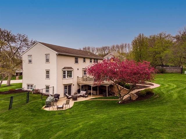 back of property featuring a lawn, a deck, a patio area, fence, and outdoor lounge area