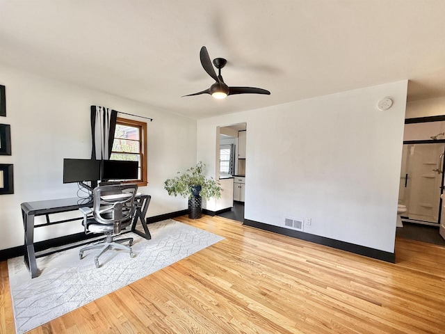 home office featuring baseboards, ceiling fan, visible vents, and wood finished floors