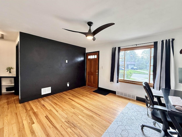 office area with visible vents, light wood finished floors, ceiling fan, and baseboards