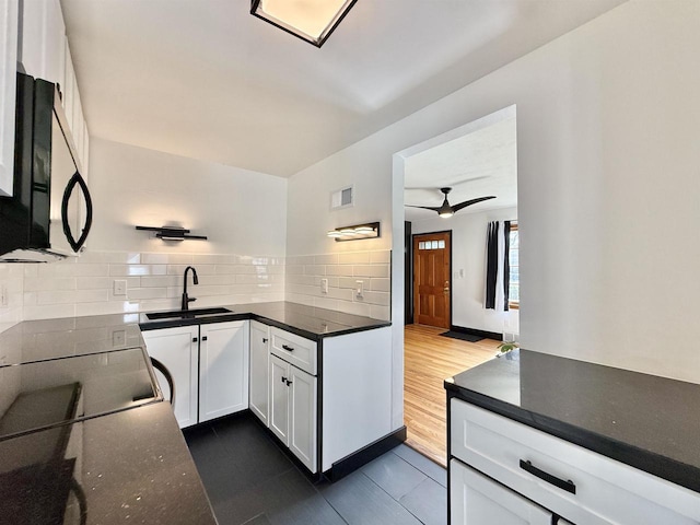 kitchen featuring black microwave, a sink, white cabinetry, tasteful backsplash, and visible vents
