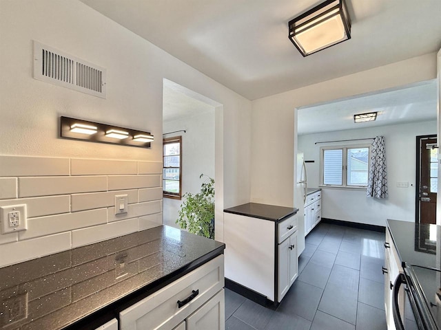 kitchen with dark countertops, a wealth of natural light, white cabinetry, and visible vents