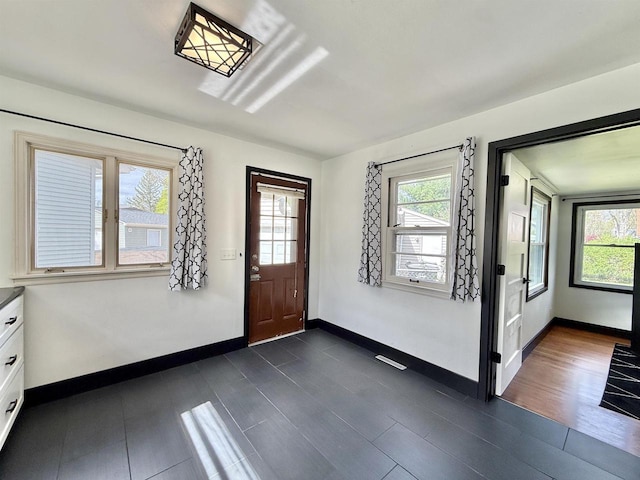 entryway with baseboards, dark wood-type flooring, and visible vents