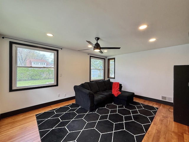 living room with visible vents, a ceiling fan, baseboards, and hardwood / wood-style floors