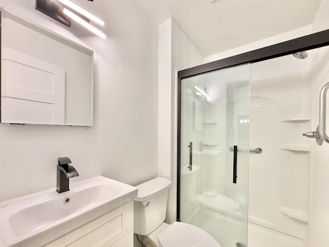 bathroom with toilet, a shower stall, and vanity
