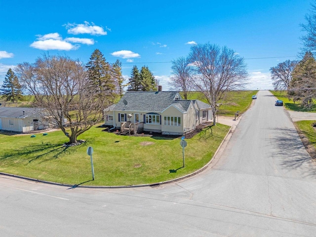 view of front of home with a chimney, driveway, and a front yard