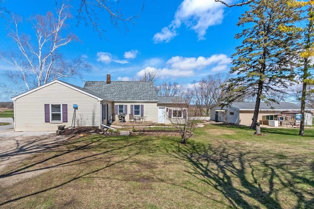 back of property featuring a wooden deck, a yard, and a chimney