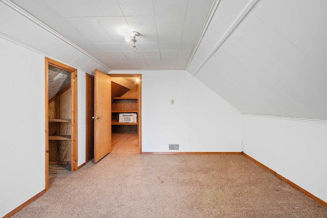 additional living space featuring carpet flooring, visible vents, baseboards, a wall unit AC, and vaulted ceiling