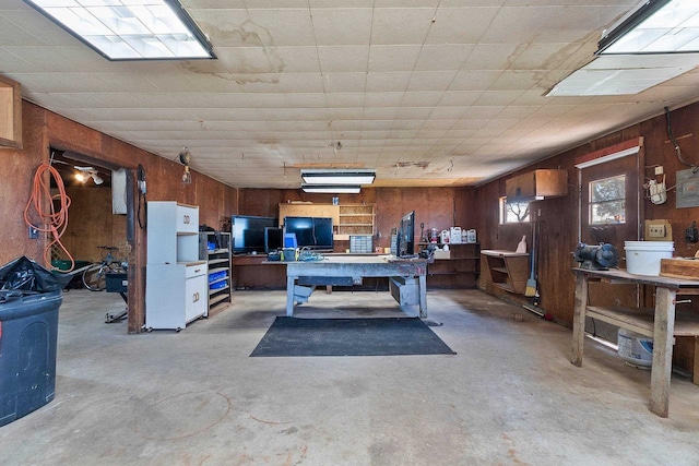 office area with concrete flooring, wooden walls, and a workshop area