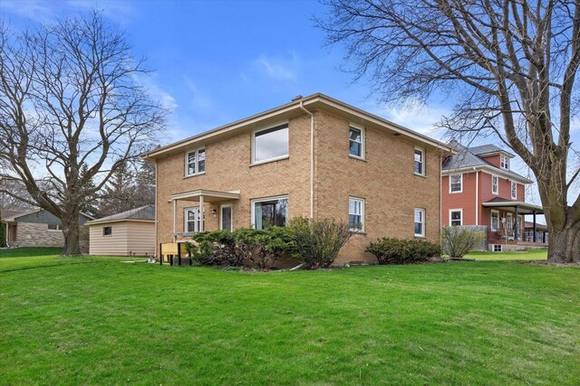 rear view of property featuring a lawn and brick siding