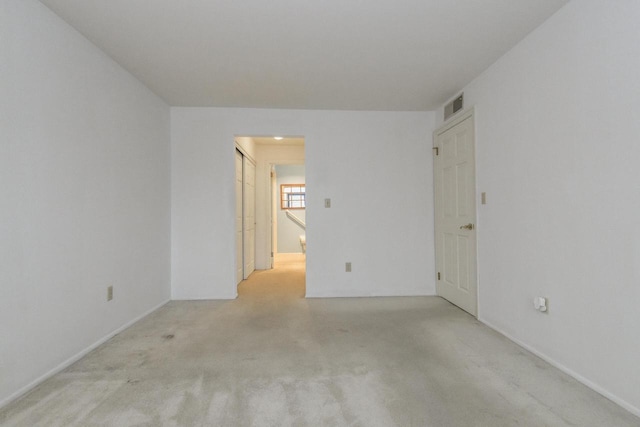 spare room with baseboards, light colored carpet, and visible vents