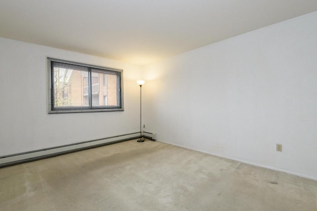 carpeted spare room with a baseboard heating unit