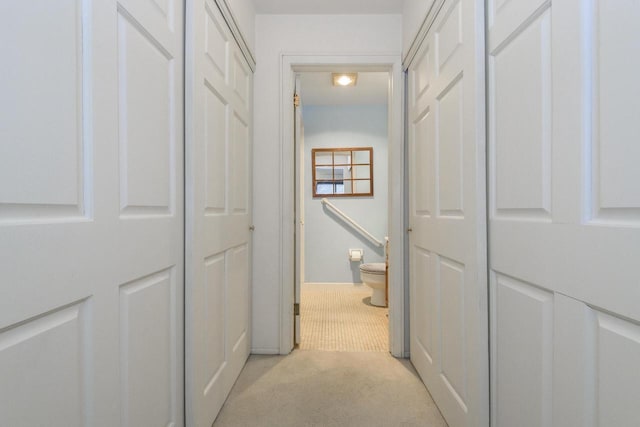 corridor featuring baseboards and light carpet