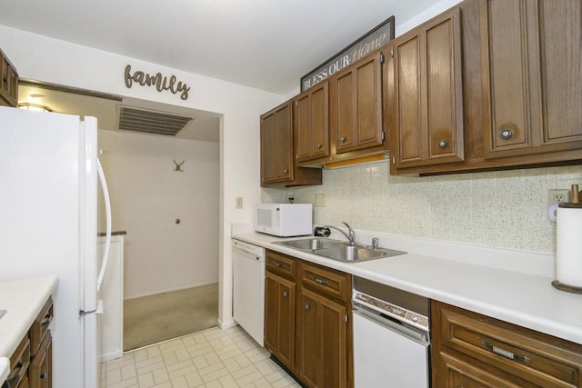 kitchen featuring visible vents, white appliances, light countertops, a sink, and backsplash