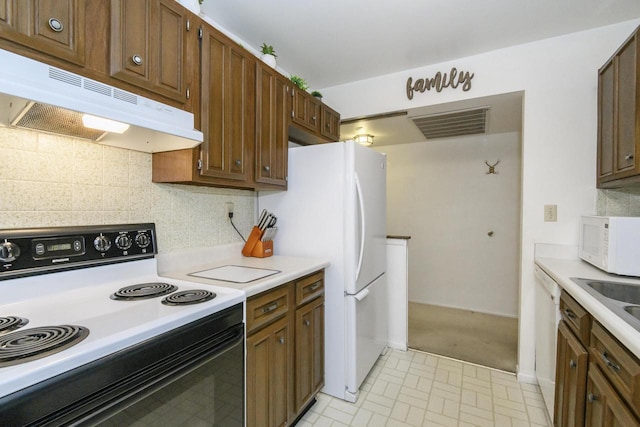 kitchen featuring light countertops, under cabinet range hood, white appliances, and visible vents