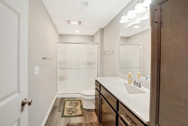 bathroom featuring a shower stall, wood finished floors, vanity, baseboards, and toilet