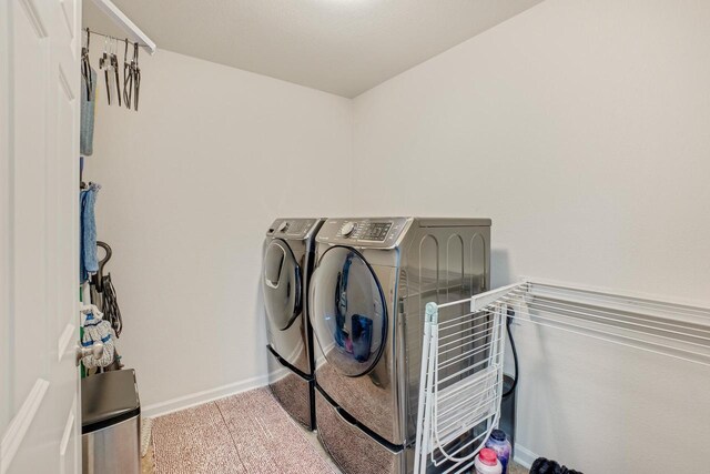 clothes washing area with laundry area, washing machine and dryer, baseboards, and carpet